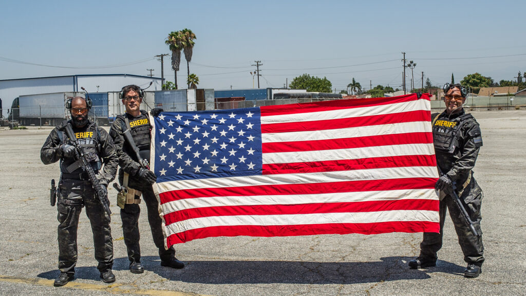 Models wearing HighCom Armor ballistic armor solutions holding American flag
